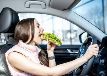 Mulher se perguntando se Comer enquanto dirige dá multa