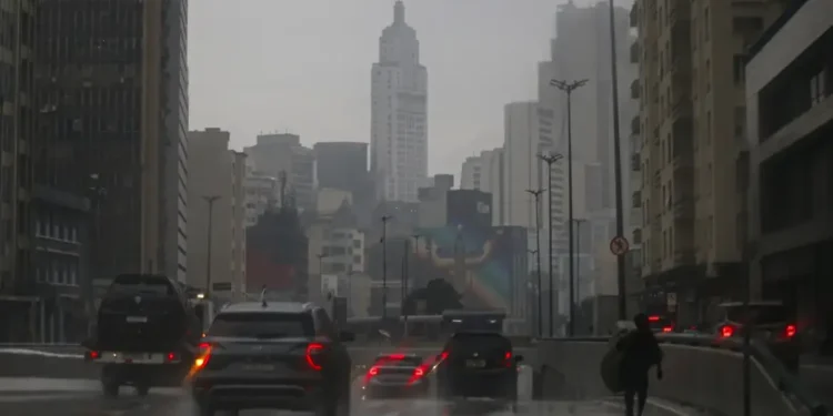 Trânsito durante um dia chuvoso na cidade, com carros e prédios ao fundo.