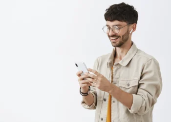Homem sorrindo e usando smartphone, com fones de ouvido, ideal para o tema de digitalização de documentos.