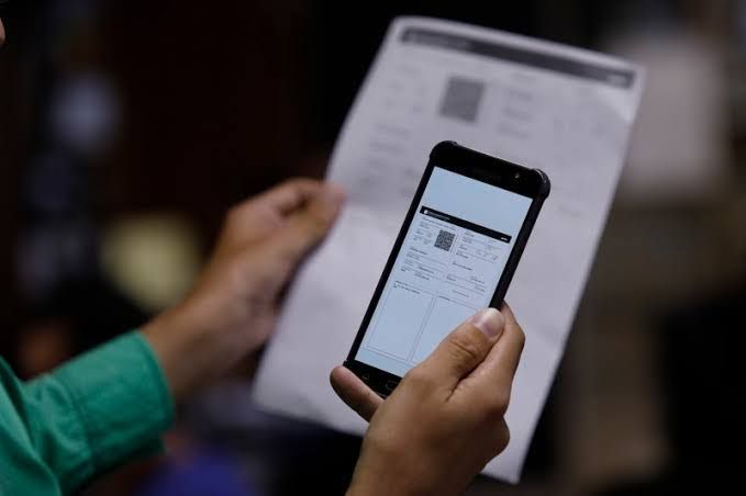 Pessoa segurando documento impresso e visualizando o CRLV digital no smartphone, processo de licenciamento de veículo