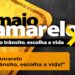 Campanha Maio Amarelo com laço amarelo e mensagem "No trânsito, escolha a vida" para conscientização sobre segurança no trânsito