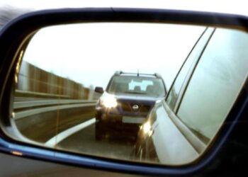 Veículo visto pelo retrovisor lateral durante uma viagem na estrada, destacando a importância da visão traseira para segurança no trânsito.