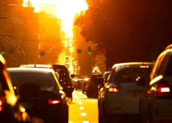 Tráfego intenso ao amanhecer com veículos na estrada e luz do sol ao fundo