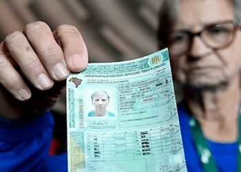 Pessoa idosa segurando a Carteira Nacional de Habilitação (CNH) em destaque