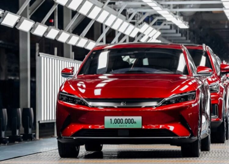 Linha de produção de carros chineses elétricos com destaque para modelo vermelho da BYD.