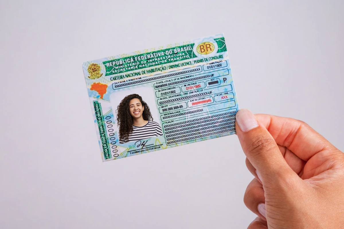 Jovem segurando a nova versão da Carteira Nacional de Habilitação (CNH) brasileira