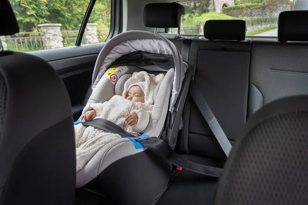 Bebê dormindo seguro em bebê conforto instalado no banco traseiro do carro