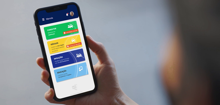 Pessoa segura o celular com o CDT digital aberto na tela, exibindo o documento do veículo pelo app oficial do governo