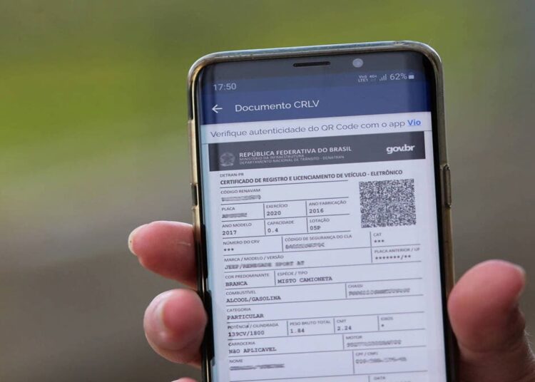 Pessoa segura o celular com o CRLV digital aberto na tela, exibindo o documento do veículo pelo app oficial do governo