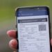 Pessoa segura o celular com o CRLV digital aberto na tela, exibindo o documento do veículo pelo app oficial do governo