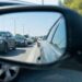Imagem mostrando o reflexo de um engarrafamento no retrovisor de um carro, com veículos parados em uma estrada. Lei do retrovisor.