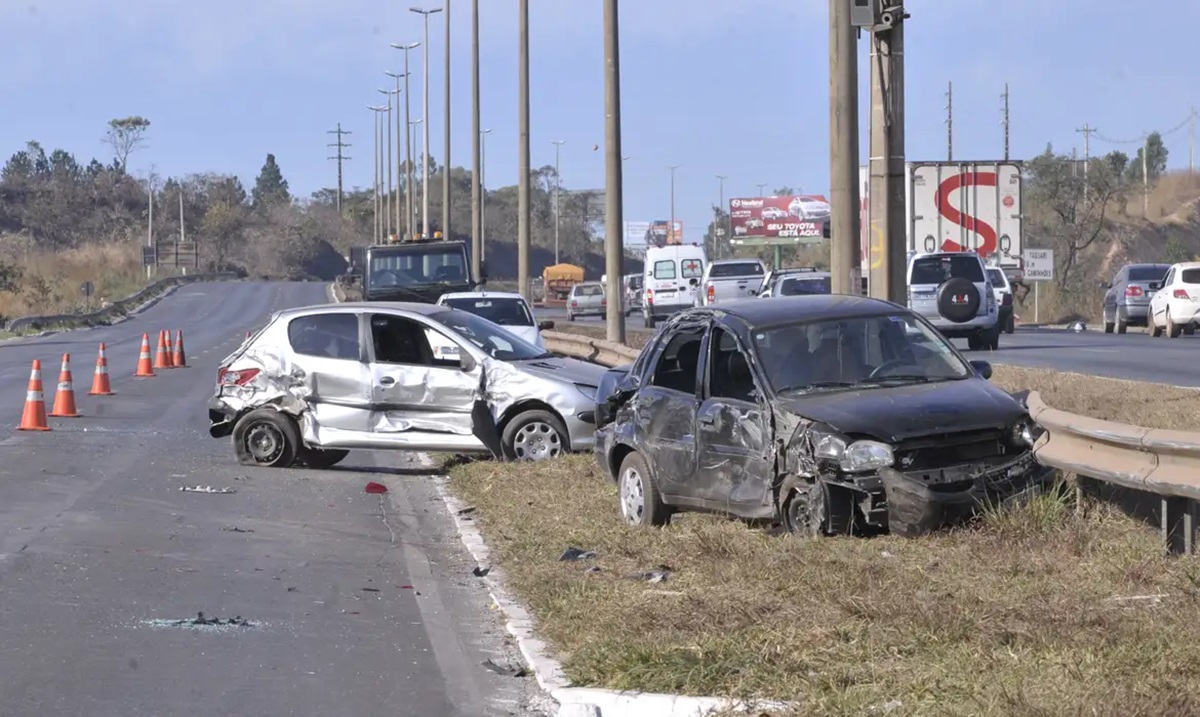 Colisão entre dois carros em rodovia com cones sinalizando área de acidente.