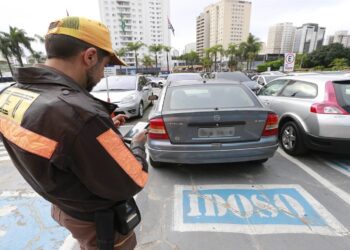 Agente de trânsito aplicando multa a carro estacionado em vaga para idosos