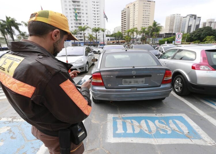 Agente de trânsito aplicando multa a carro estacionado em vaga para idosos