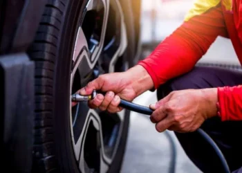 Pneu de carro totalmente murcho em contato com o chão molhado.