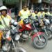 Mototaxistas em suas motos, com uniformes amarelos e capacetes, aguardando clientes