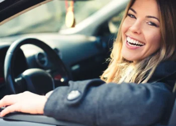 Motorista sorridente dentro do carro, demonstrando uma direção tranquila e segura.