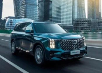 Imagem do GAC GS8, SUV grande e moderno, em movimento, com uma paisagem urbana ao fundo.
