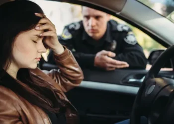 Mulher angustiada sendo abordada por policial enquanto dirige sem habilitação