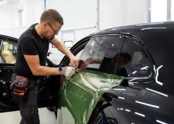 Profissional aplicando película de proteção em janela de carro
