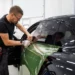 Profissional aplicando película de proteção em janela de carro