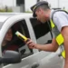 Policial realizando teste de bafômetro em motorista durante blitz de trânsito.