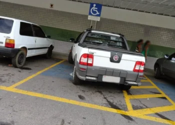Carro estacionado ilegalmente em vaga para pessoas com deficiência, violando a sinalização de estacionamento proibido."