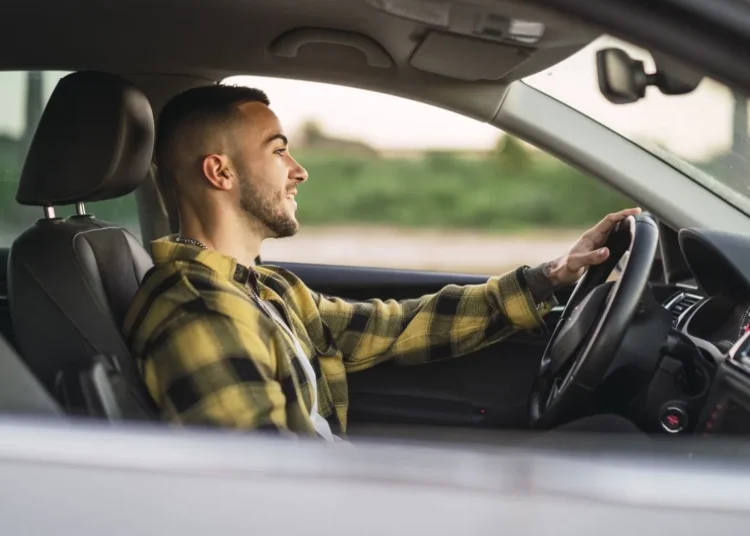 Jovem dirigindo um carro em velocidade moderada, refletindo sobre as leis de trânsito e multas por dirigir devagar.