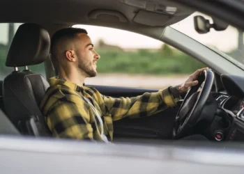Homem dirigindo com uma postura incorreta ao volante, o que pode resultar em multa.