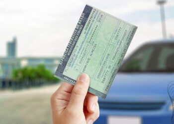 Mão segurando o Certificado de Registro e Licenciamento de Veículo (CRLV), representando a regularização de débitos como IPVA e licenciamento.