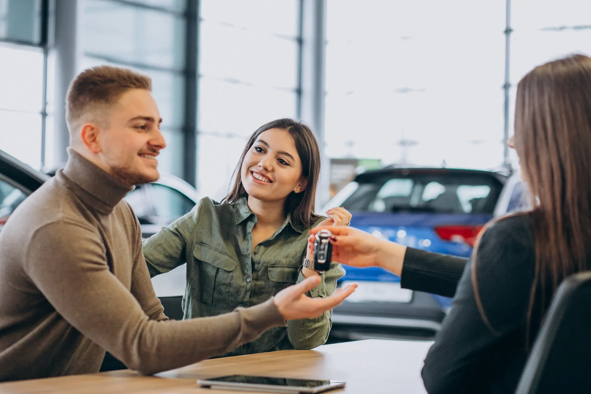 Casal discutindo condições de compra de carro com vendedor, destacando as regras para desconto MEI em modelos e versões de carros.