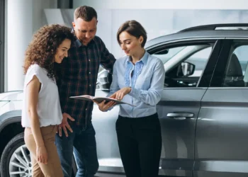 Casal recebendo orientação de vendedora em concessionária sobre benefícios de isenção de IPI na compra de veículo.