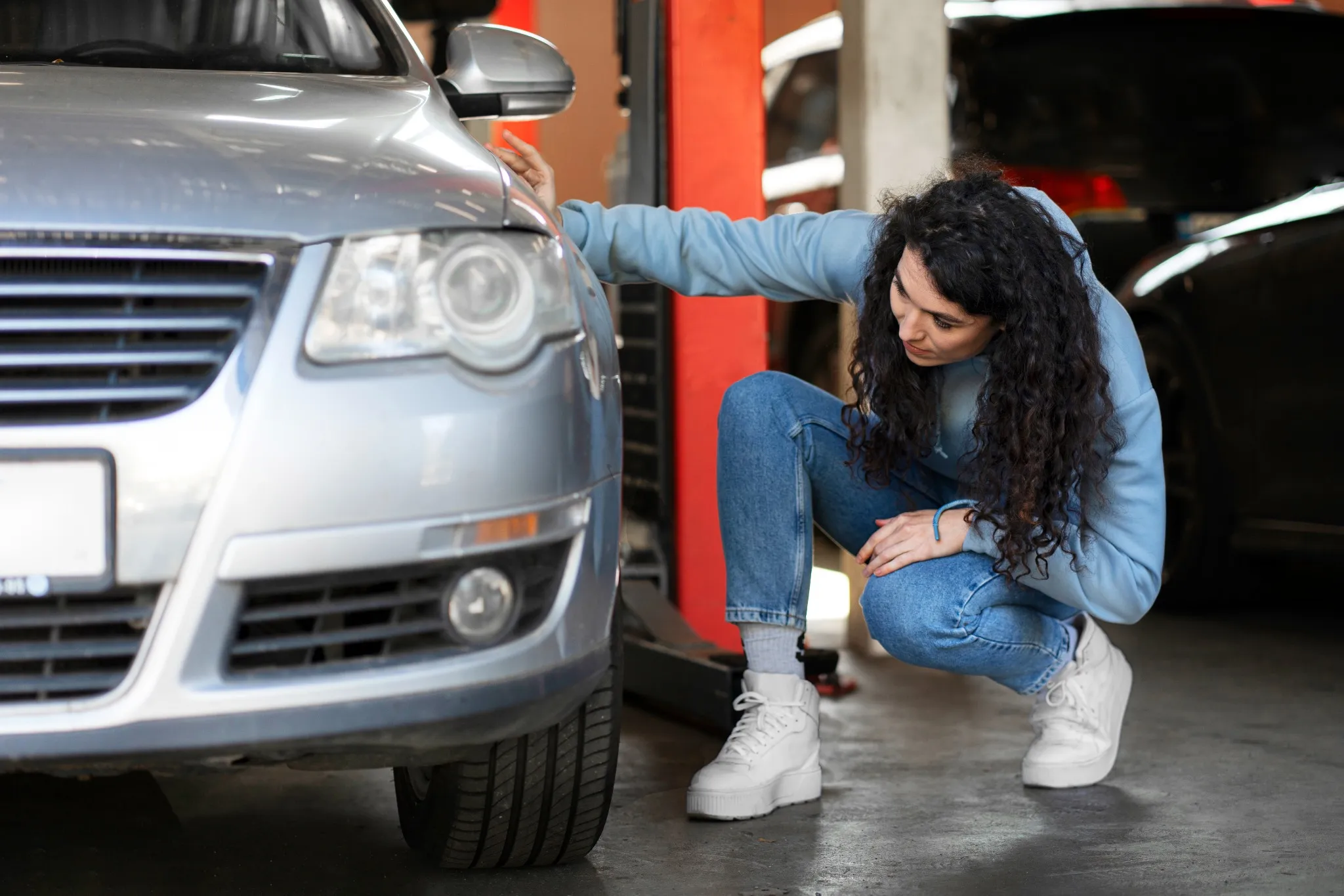 Mulher inspecionando um carro em um estacionamento, verificando detalhes como riscos e amassados.