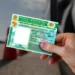 Pessoa segurando Carteira Nacional de Habilitação do Brasil com cones e carro ao fundo desfocado