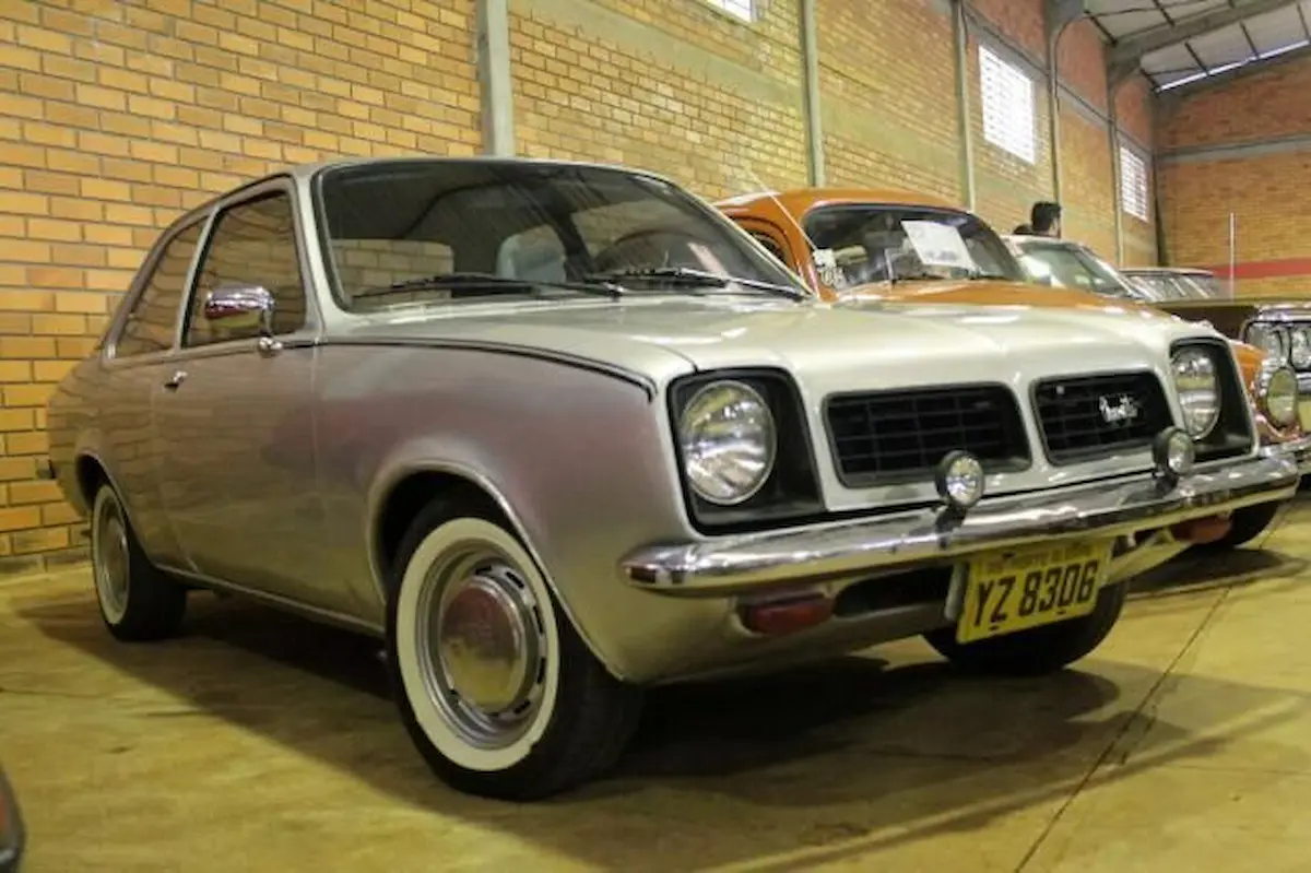 Chevrolet Chevette prata estacionado em galpão coberto com parede de tijolos ao fundo.