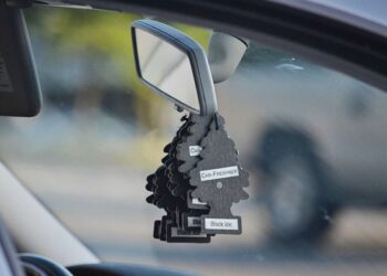 Vários aromatizadores em formato de pinheiro pendurados no retrovisor interno de um carro