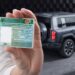 Pessoa segurando CNH brasileira ao lado de SUV elétrico estacionado em ambiente moderno