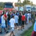 Grupo de caminhoneiros discute em frente a caminhões parados em estrada com placa de 40 km/h