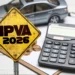 Placa amarela com texto IPVA 2026, calculadora, moedas e miniatura de carro ao fundo