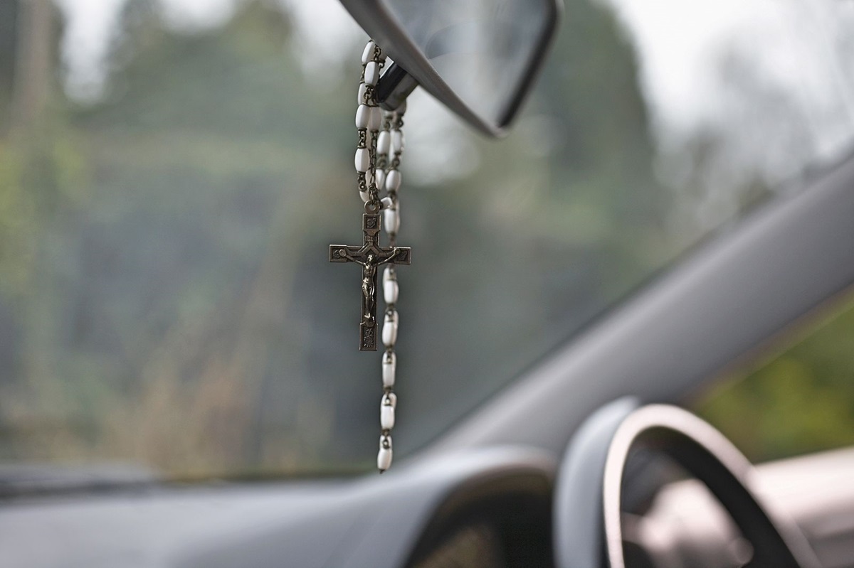 Terço com crucifixo pendurado no retrovisor interno de um carro moderno