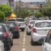 Diversos carros parados em fila dupla em avenida movimentada sob luz do dia