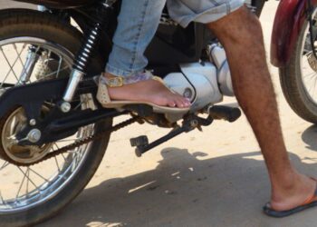Pessoas em moto vestindo sandálias e chinelo com pernas expostas próximas ao motor