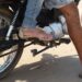 Pessoas em moto vestindo sandálias e chinelo com pernas expostas próximas ao motor