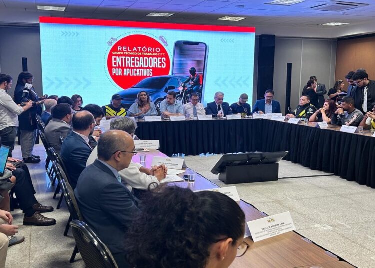 Autoridades e representantes de entregadores debatem propostas em mesa redonda, tela exibe tema da regulamentação