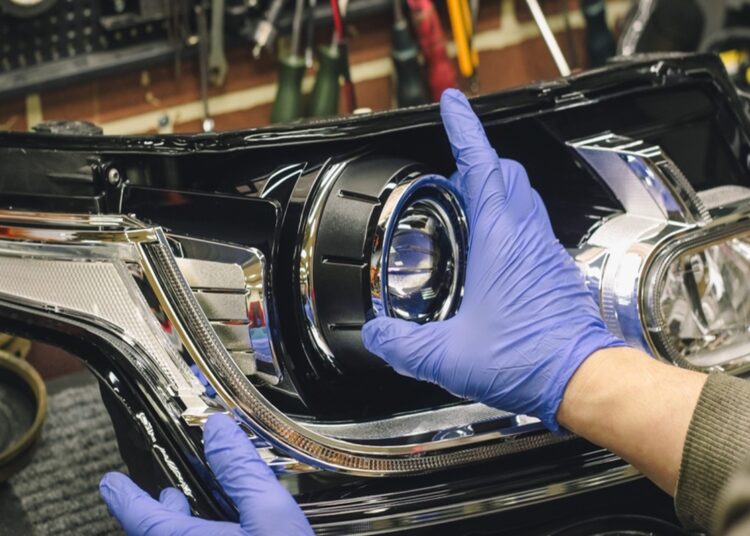 Mãos com luvas azuis ajustando farol de LED em lanterna automotiva