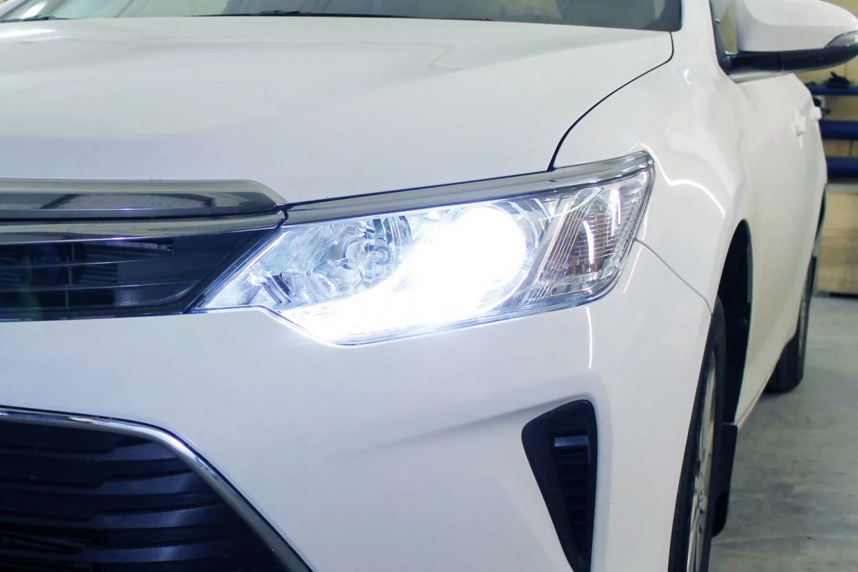 Farol de LED aceso em veículo branco em garagem iluminada