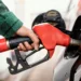 Mão segurando bico de abastecimento enquanto enche tanque de carro preto