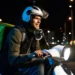 Motociclista com mochila de entrega dirige scooter à noite em avenida iluminada