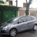Veículo cinza estacionado em frente ao portão de garagem em rua residencial