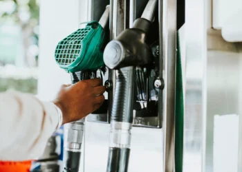 Mão retira bico verde de combustível em bomba de posto